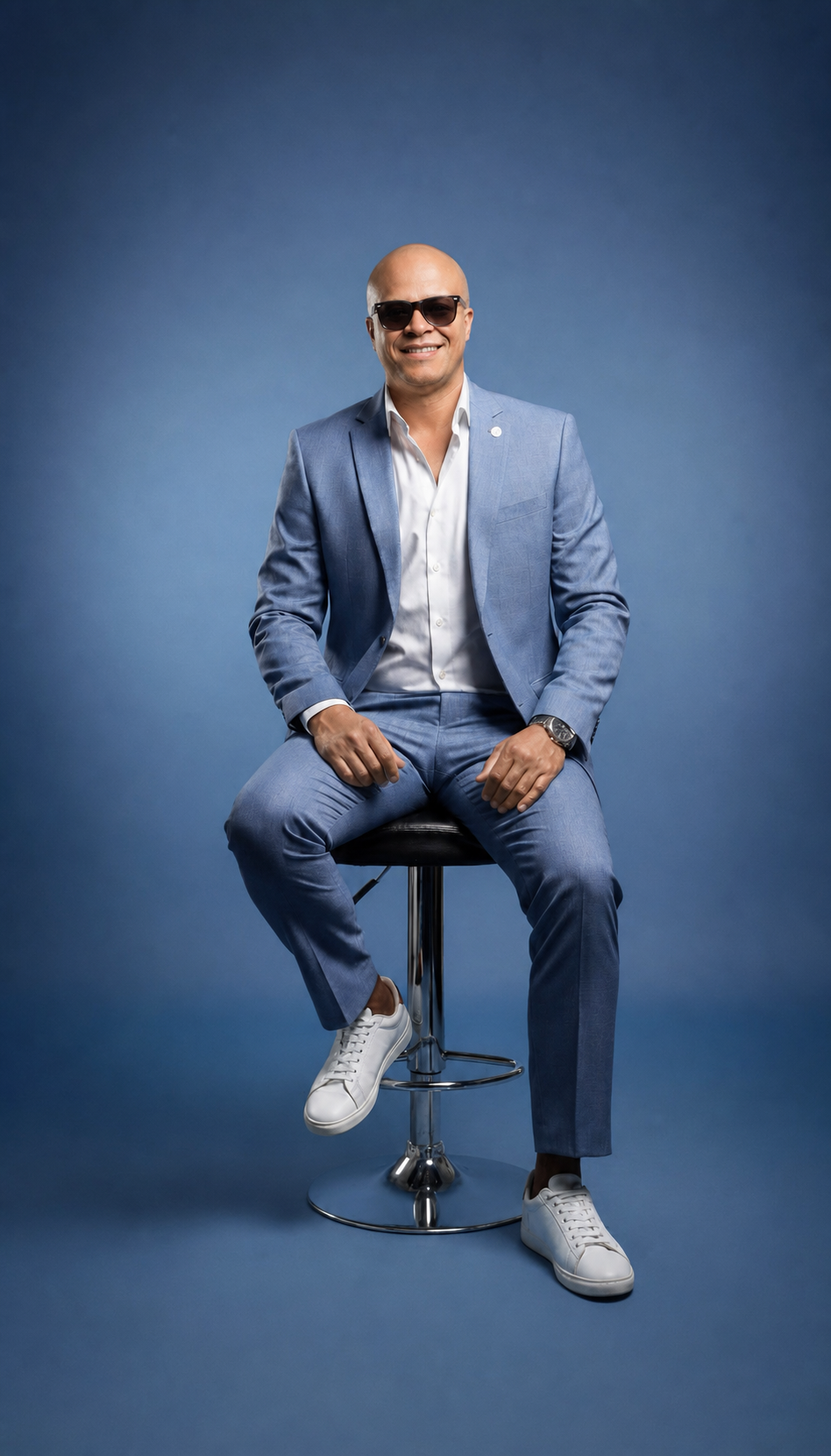 André Ferreira, sentado em um banco, vestindo terno azul